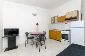 a kitchen with a table with chairs and a tv at Apartments Laguna in Stomorska