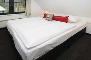 1 cama blanca grande con 2 almohadas rojas. en Semi detached houses at the Drewitzer See Drewitz, en Drewitz