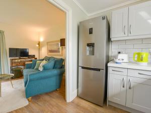 a kitchen with a blue couch and a refrigerator at Linney Cottage in Dittisham