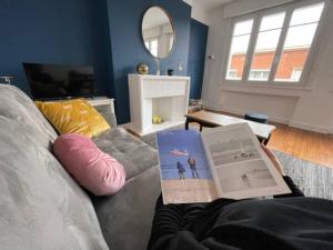 un soggiorno con divano e un libro sopra di Chez Ca&Ro, Apt lumineux entre ville et mer a Dunkerque