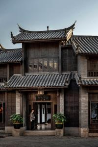 Un uomo in piedi sulla porta di un edificio di Lijiang Ancient City Anyu Hotel a Lijiang