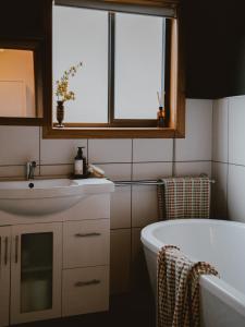 a bathroom with a sink and a tub and a window at Sunken Sea Shack - waterfront getaway in Eggs and Bacon Bay