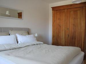 1 cama con sábanas blancas y armario de madera en Schönhier-Vimmendorf, en Timmendorfer Strand
