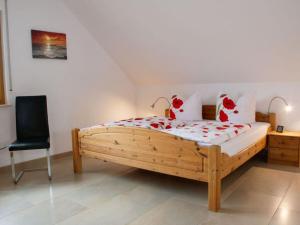 - une chambre avec un lit en bois et une chaise noire dans l'établissement Holiday apartment Thoma, à Königheim