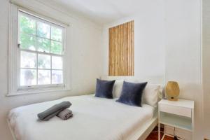 a bedroom with a bed with blue pillows and a window at Delightful 2 Bedroom House Pyrmont 2 E-Bikes Included in Sydney
