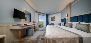 ein Hotelzimmer mit einem großen Bett und einem TV in der Unterkunft Pine Beach Belek in Belek