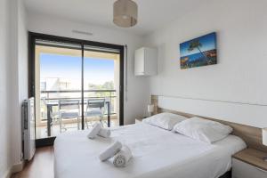 1 Schlafzimmer mit 2 Betten und Blick auf einen Balkon in der Unterkunft Appartement Tavernia - Welkeys in Mandelieu-la-Napoule