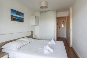 ein Schlafzimmer mit einem weißen Bett mit zwei Handtüchern darauf in der Unterkunft Appartement Tavernia - Welkeys in Mandelieu-la-Napoule
