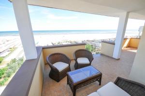 a balcony with chairs and a table and the beach at Hotel Plaza in Lido degli Estensi