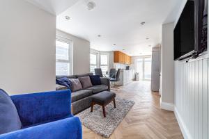 a living room with a blue couch and a tv at Amazing 2BR flat wprivate garden, Maida Vale in London