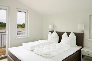 Una cama blanca con almohadas blancas encima. en Holiday homes by the lake in the Geesthof holiday park Hechthausen en Hechthausen