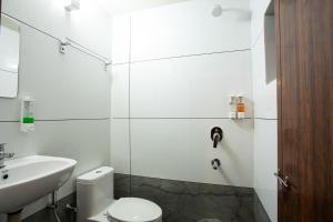 a white bathroom with a toilet and a sink at JK Lodge in Kottayam