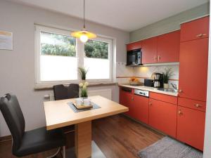cocina con armarios rojos y mesa de madera en Apartment in Ostseebad Ahrenshoop, en Wustrow