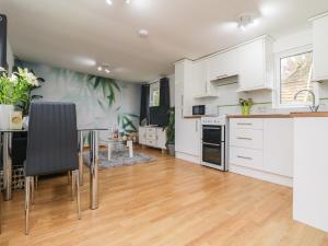 a kitchen with white cabinets and a dining table at Palm Lodge in Penzance