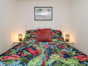 a bed with a colorful comforter and a red pillow at Palm Lodge in Penzance
