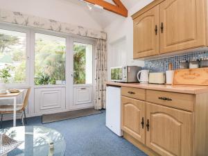 a kitchen with wooden cabinets and a glass table at Lighthouse in Penzance