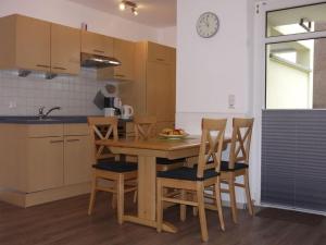 eine Küche mit einem Tisch und Stühlen sowie einer Uhr an der Wand in der Unterkunft 1 in Haus Weser 1 in Cuxhaven
