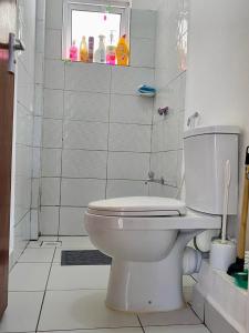 een witte badkamer met een toilet en een raam bij GIANA Stays with a pool in Mombasa