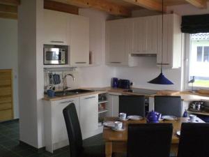 a kitchen with white cabinets and a wooden table at Holiday home water view in Quilitz