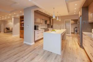 a large kitchen with a white counter top and wooden floors at Waterstone Villa in Hermanus