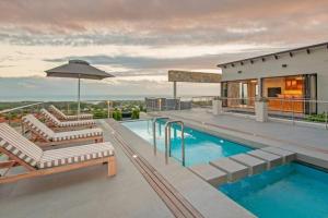 a house with a swimming pool and lounge chairs at Waterstone Villa in Hermanus