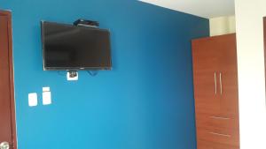 TV de pantalla plana en una pared azul en una habitación en Hostal Costa Azul en Manta