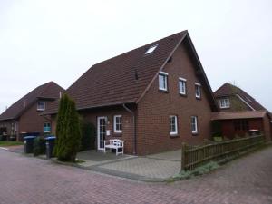 een groot bakstenen huis met een witte bank ervoor bij Holiday home Christmann in Hooksiel