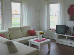 ein Wohnzimmer mit einem Sofa und einem TV in der Unterkunft Holiday home in Wietzendorf in the L neburg Heath with a view of the countryside in Wietzendorf