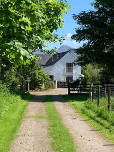 a dirt road in front of a white barn at Drimnatorran Farm Lodge in Strontian