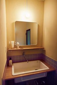 een badkamer met een bad en een spiegel bij Aoyado - Tottori Aoya in Tottori