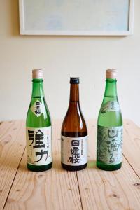 drie flessen bier zittend op een houten tafel bij Aoyado - Tottori Aoya in Tottori