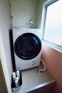 uma máquina de lavar roupa numa casa de banho ao lado de uma janela em Aoyado - Tottori Aoya em Tottori