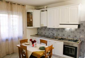 een keuken met witte kasten en een tafel met stoelen bij Appartamento centrale in Tortona