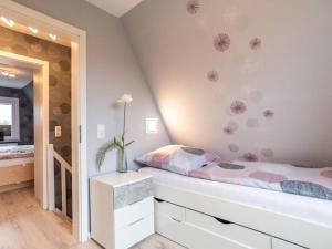 ein Schlafzimmer mit einem Bett und einer Vase aus Blumen an der Wand in der Unterkunft Holiday home Villa Maiwaldo in Spieka-Neufeld