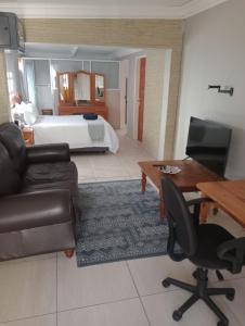 ein Wohnzimmer mit einem Bett, einem Sofa und einem Schreibtisch in der Unterkunft La Cordier in Kroonstad