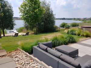 a couch sitting in the grass next to a body of water at Holiday house house on Mühlfeldsee in Löbnitz