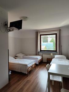 トゥシンにあるPokoje Gościnne Soniaのベッド3台と窓が備わる客室です。