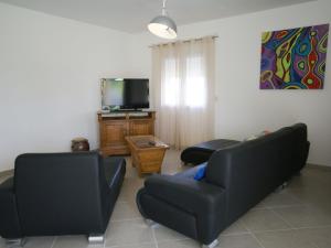 a living room with two black couches and a tv at Chic Holiday Home in Pradons with Swimming Pool in Pradons