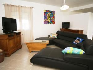 a living room with a black couch and a flat screen tv at Chic Holiday Home in Pradons with Swimming Pool in Pradons