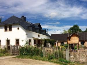 a white house with a black roof and a fence at Holiday apartment wellness & relaxation in Wunsiedel