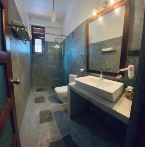 a bathroom with a sink and a toilet and a mirror at Jumelle Residence in Horetuduwa