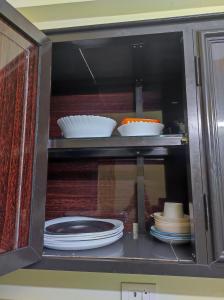 a cabinet filled with plates and bowls and dishes at 1 BHK Flat in Kochi 904 in Cochin