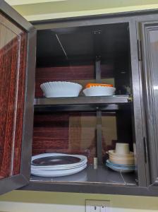 a cabinet filled with plates and bowls and dishes at 1 BHK Flat in Kochi 904 in Cochin +37 photos