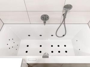 uma banheira com um chuveiro e uma cabeça de chuveiro em Mosel Sky Lounge with loggia & panoramic view em Kenn