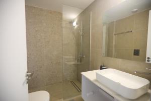 une salle de bain avec un lavabo blanc et une douche dans l'établissement Eva Residences- Kapparis, à Paralímni 39 autres photos