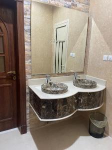 a bathroom with two sinks and a large mirror at شاليه سهم in Al Khobar