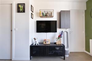 a living room with a tv on a white wall at Charmant studio tout confort in Paris