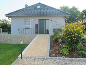 uma pequena casa branca com um jardim com flores amarelas em Detached holiday home in an idyllic quiet location em Kleinwinklarn