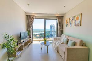 a living room with a couch and a large window at The Song Apartment - CONDOTEL BUNNY HOME VUNG TAU in Vung Tau