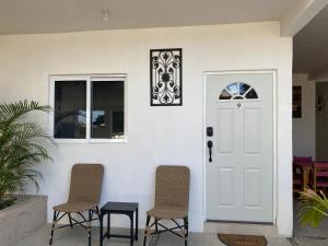 une porte blanche avec deux chaises et une table dans l'établissement Casa del sol, à San José del Cabo